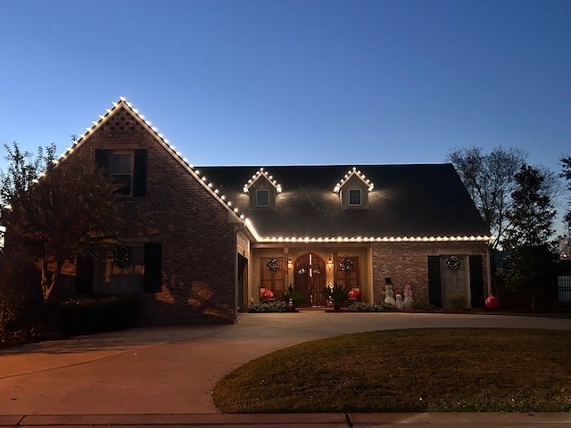 Brick home with professional Christmas lights at dusk