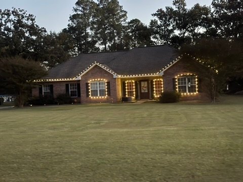 Brick ranch home with roofline lighting in daylight