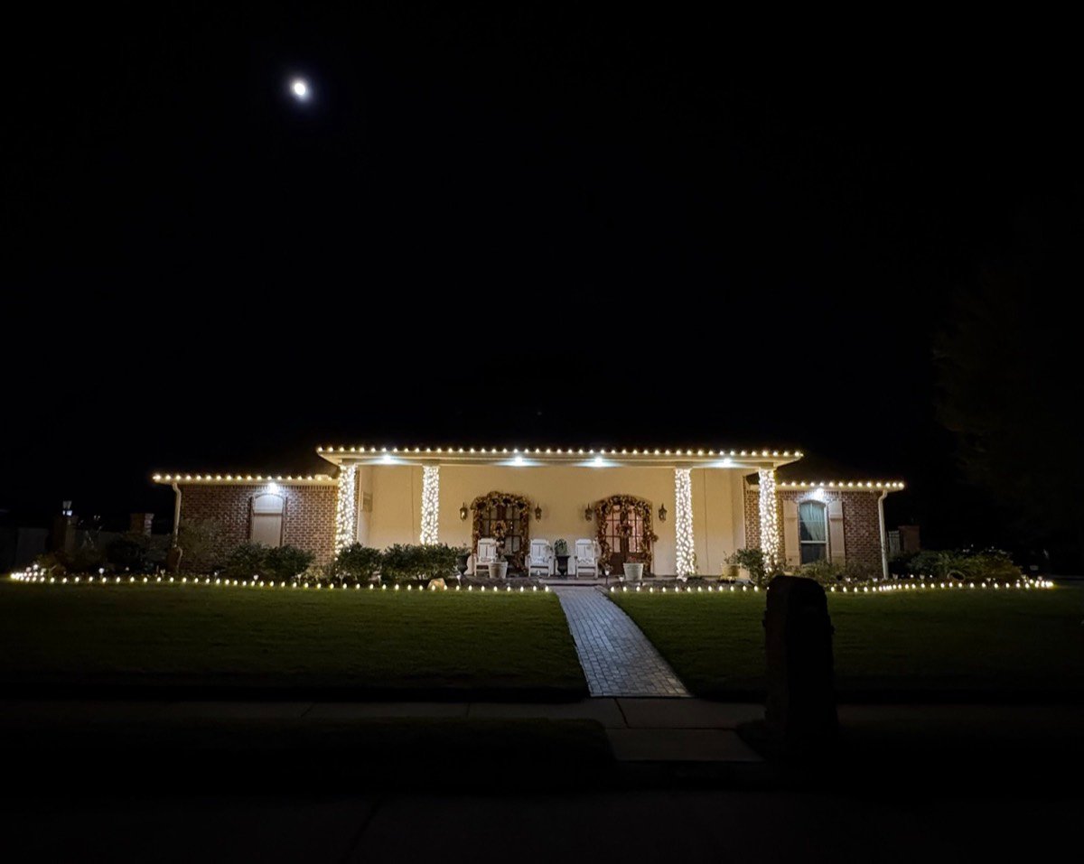 Moonlit estate with wrapped columns and wreathed doors